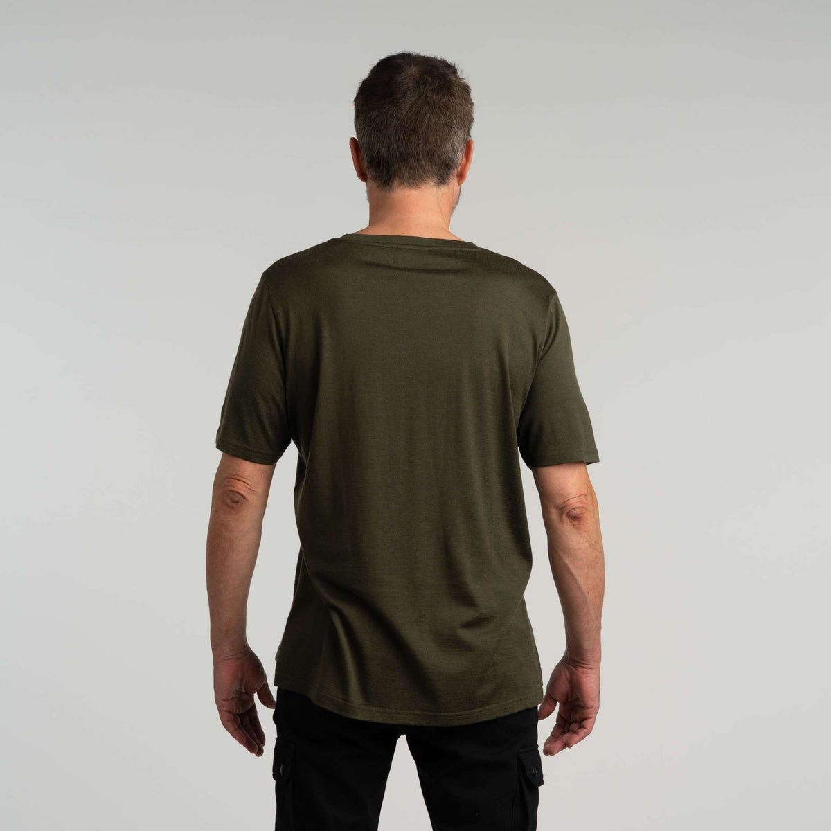 North Outdoor Liam miesten merino T-paita värissä tumma oliivi, mulesing-vapaa merinovilla. Suunniteltu Suomessa. - Malli on 181 cm ja käyttää kokoa L
