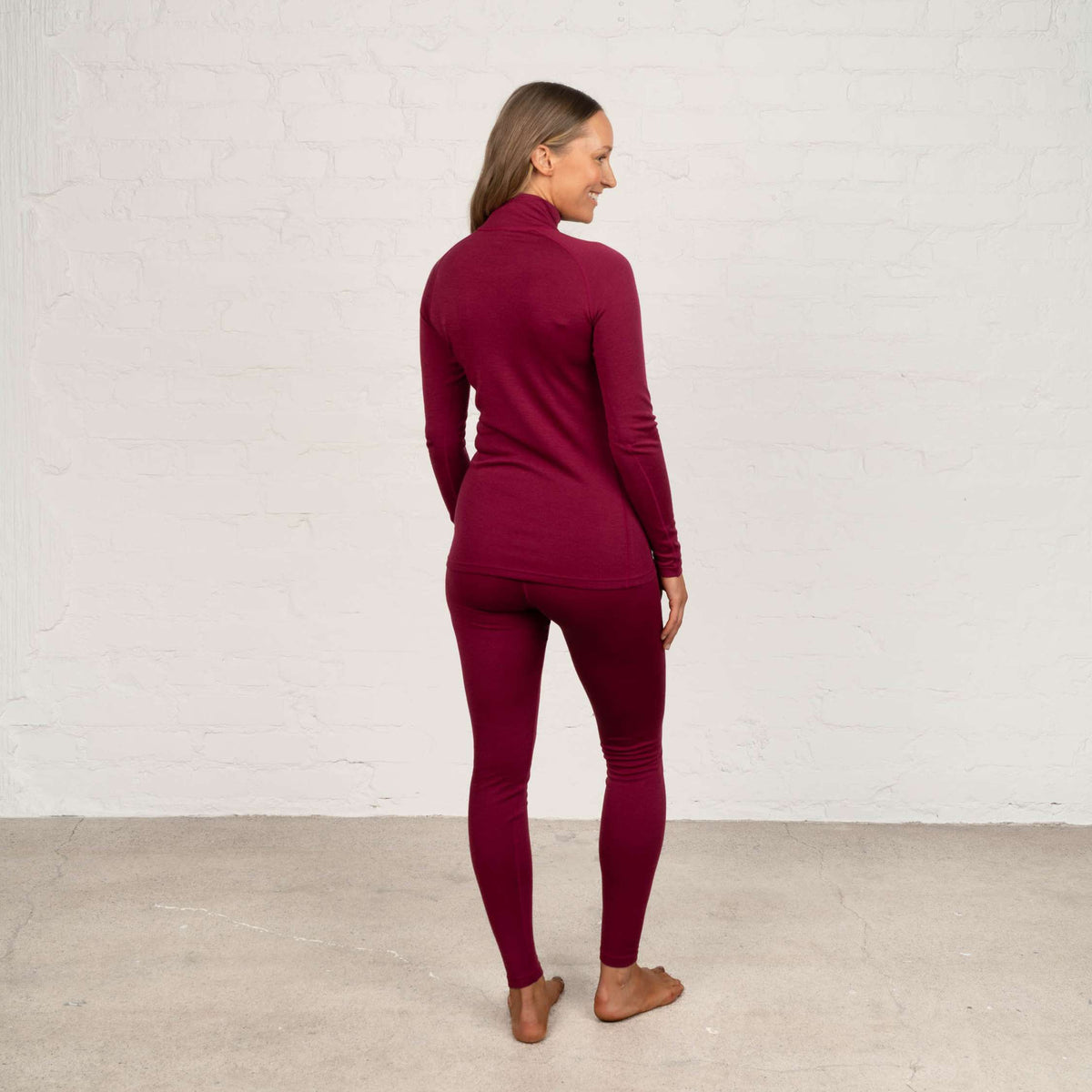 North Outdoor Maglia intima in merino Sensitive 225 da donna con collo alto e zip, nel colore rubino, senza mulesing Lana merino. Progettata in Finlandia. Perfetta per il layering tecnico. - Il modello è alto 174 cm e indossa la taglia S